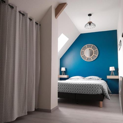 - une chambre bleue avec un lit et un miroir dans l'établissement La Grange aux Abeilles 3, à Saint-Senier-sous-Avranches