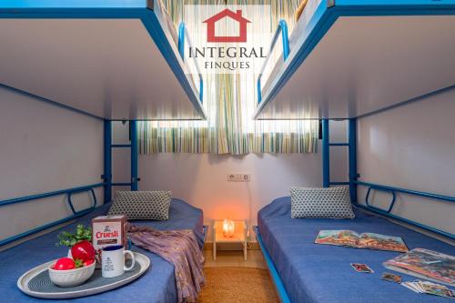 a room with two beds and a table with a tray of food at Apartament Cel Blau in Palamós