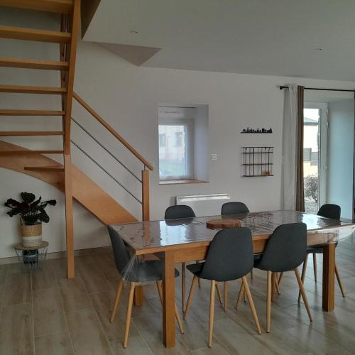 une salle à manger avec une table et des chaises et un escalier dans l'établissement La Grange aux Abeilles 3, à Saint-Senier-sous-Avranches