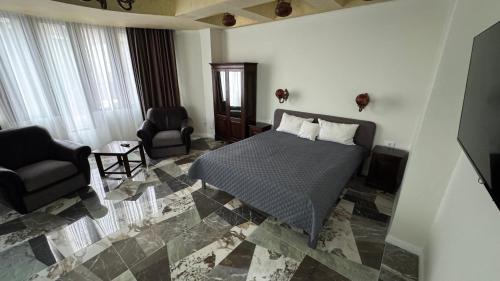 a bedroom with a bed and two chairs in it at Hotel Majestic in Iaşi