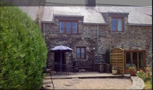 a stone house with an umbrella in front of it at Grange Cottage in Saint-Dolay