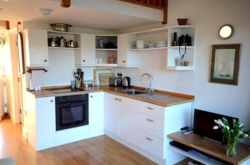 a kitchen with white cabinets and a sink at Steepfield Studio in the heart of Bantham Village in Bigbury on Sea