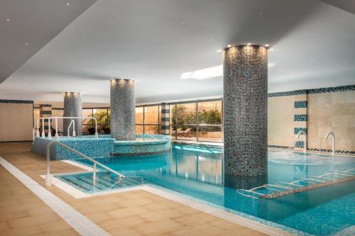 a large swimming pool with two pillars in a building at Grande Real Santa Eulalia Resort & Hotel Spa in Albufeira