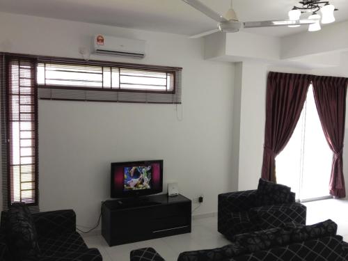 een woonkamer met 2 stoelen en een flatscreen-tv bij Comfort Holiday Home @ Bukit Indah in Johor Bahru