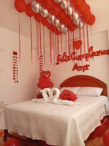 a bedroom with a bed with red hearts and balloons at Hospedaje La Cascada in Tacna