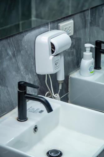 a bathroom sink with a hair dryer on a mirror at Kiwi Capsule Hotel in Bangkok