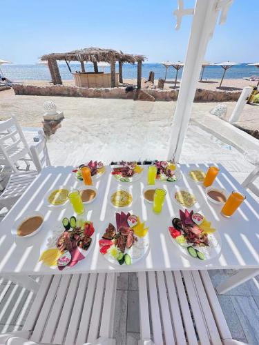 a table with plates of food on the beach at Nubia Island View Dahab in Dahab