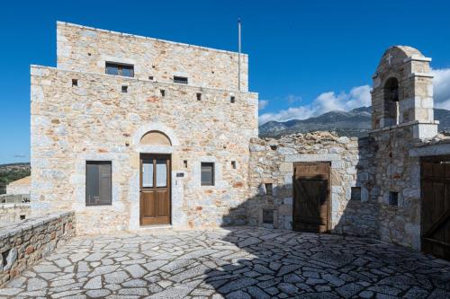 a large stone building with a clock tower on it at Tzokeika Traditional Settlement in Riglia