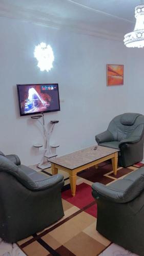 a living room with two chairs and a table and a tv at général in Yaoundé