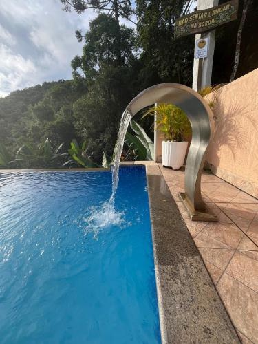 a swimming pool with a water fountain at Casa, hidro, piscina, aconchego e uma linda vista! in Mairiporã