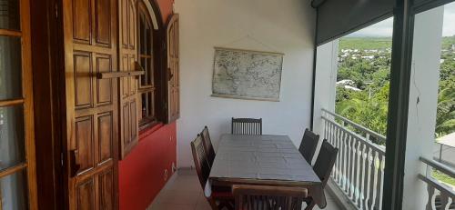 een eetkamer met een houten tafel en een balkon bij Appartement LONGANIS in Saint-Gilles-les-Bains