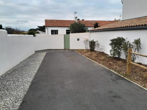 une allée vide devant une clôture blanche dans l'établissement La Maison du Clocher, à Rivedoux-Plage