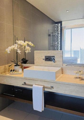 a bathroom with a counter with a sink and flowers at Fraser Suites Diplomatic Area Bahrain in Manama