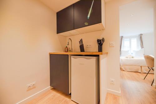 Cette chambre comprend un lit et une cuisine équipée d'un réfrigérateur. dans l'établissement CIA - Studio Pierre Fontaine, à Paris