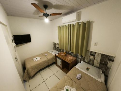 Cette chambre comprend deux lits et un ventilateur de plafond. dans l'établissement Pousada São Judas Tadeu, à Cachoeira Paulista