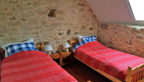 - 2 lits dans une chambre aux murs de briques dans l'établissement Lagrenie, à Groléjac