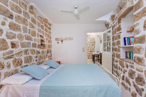 1 dormitorio con 1 cama azul en una pared de piedra en Peti Apartment, en Dubrovnik