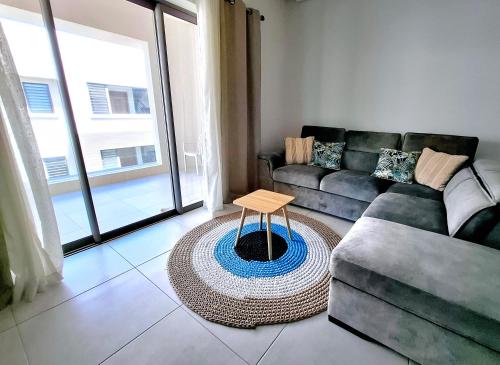 Soleia 2 - Pereybere - Appartement Cozy avec piscine proche plage في غراند بايَ: غرفة معيشة بها أريكة وطاولة