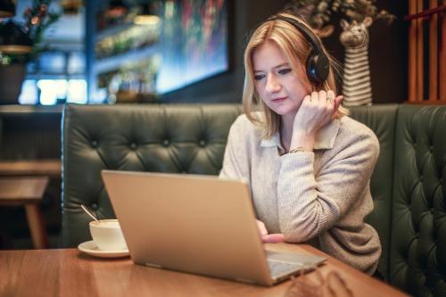 a woman wearing headphones sitting at a table with a laptop at The Circus Hotel in Berlin