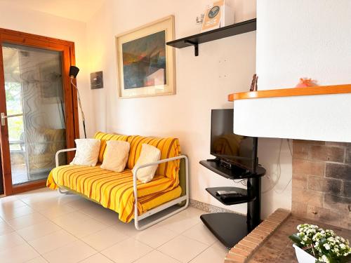 a living room with a yellow couch and a tv at Patio on the Simius beach in Simius