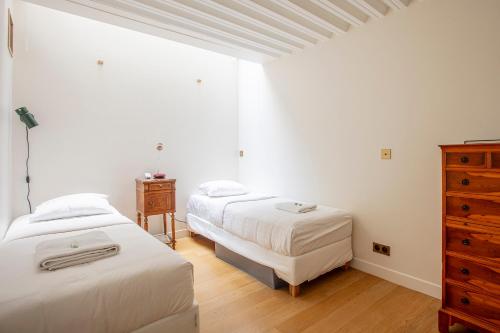 - une chambre avec 2 lits et une commode dans l'établissement Parisian loft with plenty of light and solarium in Bastille area, à Paris