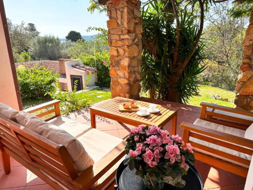 a patio with a table and benches and flowers at Patio on the Simius beach in Simius