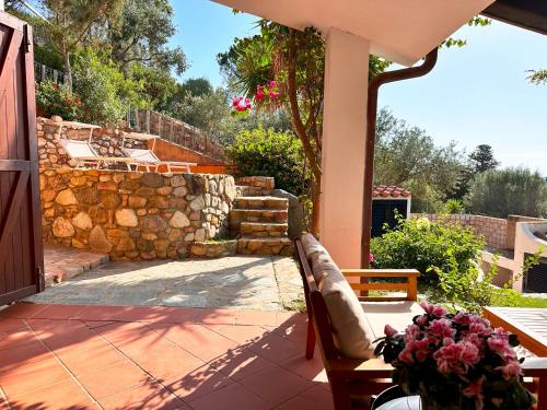 a patio with a bench and a stone wall at Patio on the Simius beach in Simius