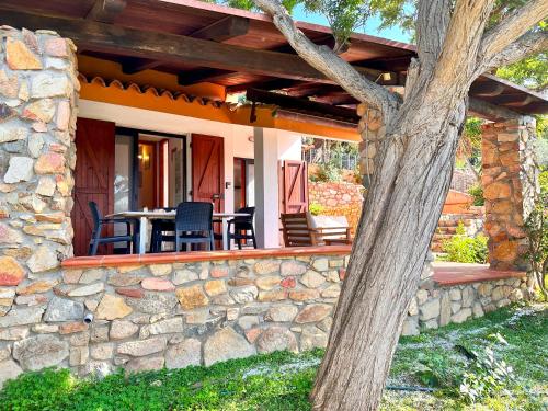 a patio with chairs and a table on a stone wall at Patio on the Simius beach in Simius