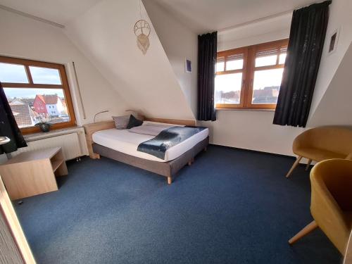 a small bedroom with a bed and two windows at HOTEL BIKE & HIKE in Obersuhl