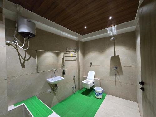 a bathroom with a toilet and a sink with a green floor at Hotel Vilaasitaa inn Ujjain in Ujjain