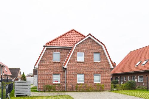 een rood bakstenen huis met een rood dak bij Ferienhaus Lüttje Krabbe in Carolinensiel
