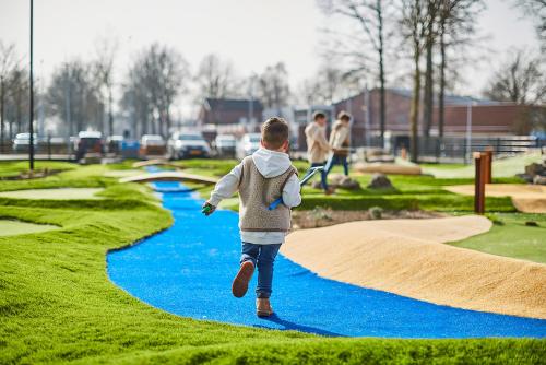 a young boy is running on a miniature golf course at Recreatiepark de Leistert in Roggel