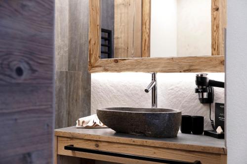 a bathroom with a stone sink and a mirror at Chalet-Suite Wald in Selva dei Molini
