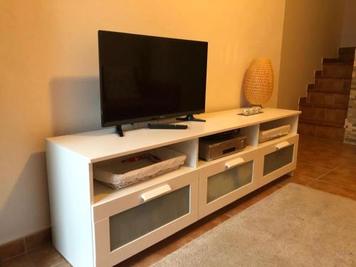 un centro de entretenimiento blanco con TV de pantalla plana. en Charming Town house, en Ardales