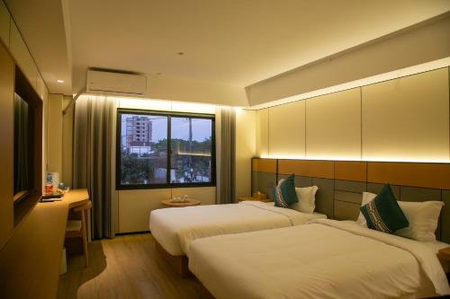 a hotel room with two beds and a window at Ruby Hotel in Vientiane