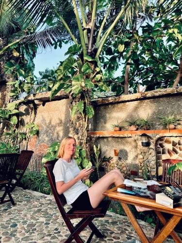 a woman sitting in a chair at a table at Sầm Sơn Boutique Hotel Phan Thiết in Phan Thiet