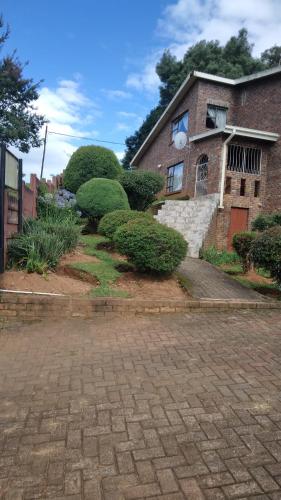 a brick house with bushes in front of it at Hamba Kancane Ma-Africa Guest House in Graskop