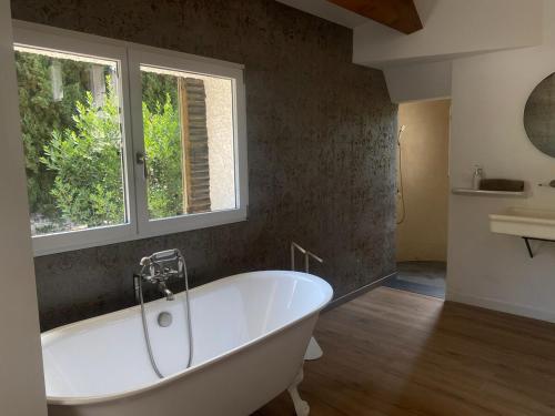 La salle de bains est pourvue d'une baignoire blanche et d'une fenêtre. dans l'établissement Luxury Villa Cleopatra, private pool in heart of nature for 2 people, à Quarante