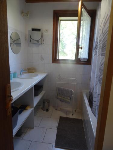 La salle de bains est pourvue d'un lavabo, d'une baignoire et d'une fenêtre. dans l'établissement Le Pinada, entre Saint Emilion et Bergerac, à Montcaret