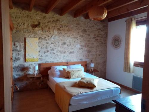 MontcaretにあるLe Pinada, entre Saint Emilion et Bergeracのベッドと石の壁のある寝室