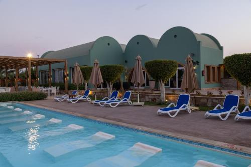 a pool at a hotel with chairs and umbrellas at Novotel Marsa Alam Beach Resort in Quseir