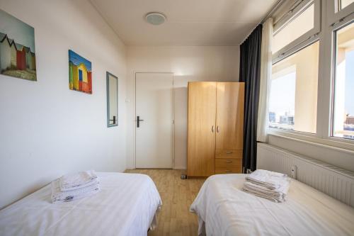 Habitación con 2 camas y armario con ventanas. en The Lookout, en Egmond aan Zee