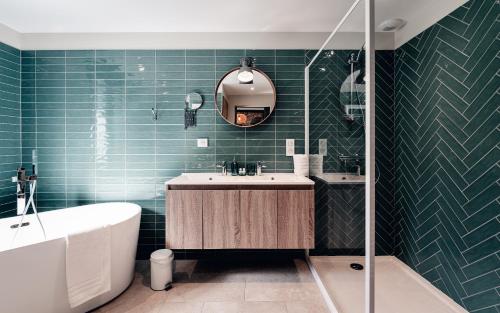 a bathroom with green tiles and a tub and a sink at La Maison des Pins contis in Saint-Julien-en-Born