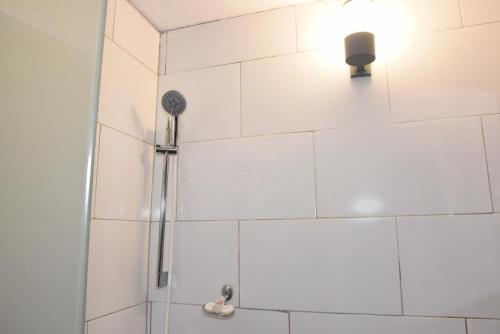a shower with a shower head on a white tiled wall at Hostel Gato Colonial in Santo Domingo