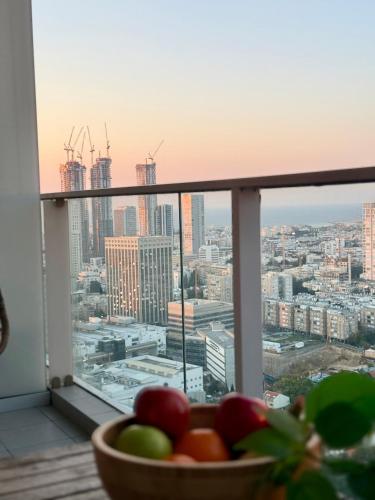 a bowl of fruit on a balcony with a view of a city at Midtown Tel Aviv Luxury Apartment in Tel Aviv
