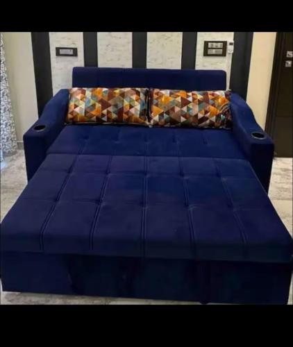 a blue couch with a pillow on top of it at Modern Luxury Deecon Valley 2BHK Flats 3Double Beds with Terrace View Tapovan Rishikesh in Rishīkesh