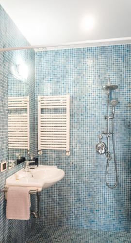 a blue tiled bathroom with a sink and a shower at Panoramic villa with pool in Bolsena