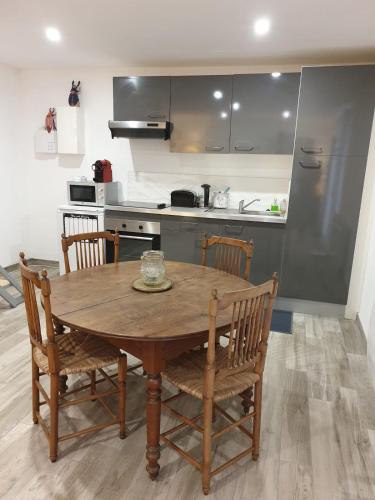 une cuisine avec une table et des chaises en bois ainsi qu'une cuisine avec un comptoir dans l'établissement La Grange des Tilleuls, à Lantenay