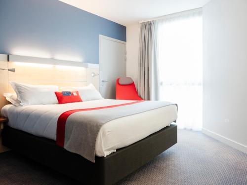 a bedroom with a large bed with a red chair at Holiday Inn Express Saint-Nazaire by IHG in Saint-Nazaire