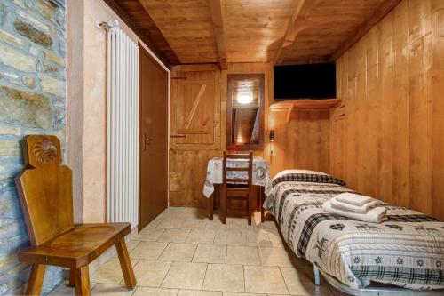 a bedroom with a bed and a chair in a room at Arthemisia - Rhêmes-Notre-Dame in Rhêmes-Notre-Dame